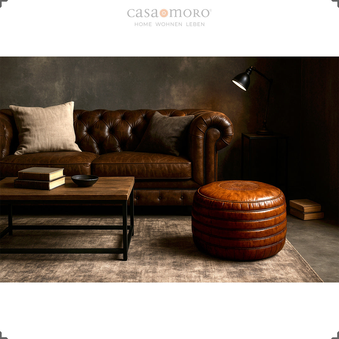 Elegantes Wohnzimmer mit Chesterfield-Sofa, Couchtisch und rundem Leder Pouf in Braun – stilvolle Szene im Industrial- und Modern-Rustic-Stil.