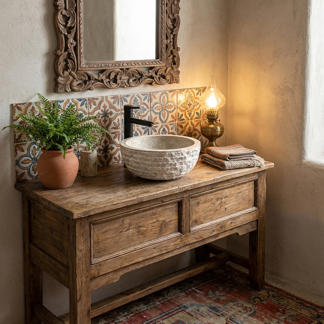 Lavabo redondo con apariencia de mármol hecho de piedra sobre un tocador de madera rústica en un cálido baño vintage con azulejos