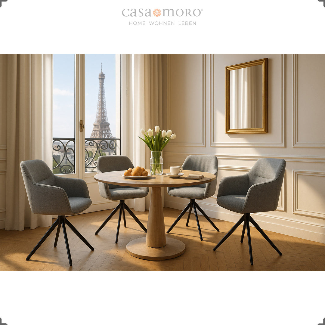 Vier 360° drehbare Polsterstühle mit Armlehnen in Grau um einen runden Holztisch in elegantem Esszimmer mit Ausblick auf den Eiffelturm
