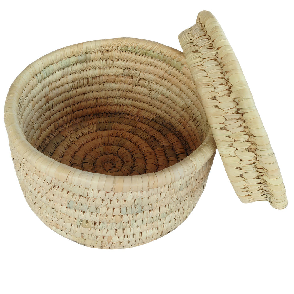 Cesta redonda trenzada de hoja de palma, de 28 cm de diámetro, con tapa apoyada lateralmente y interior a la vista.