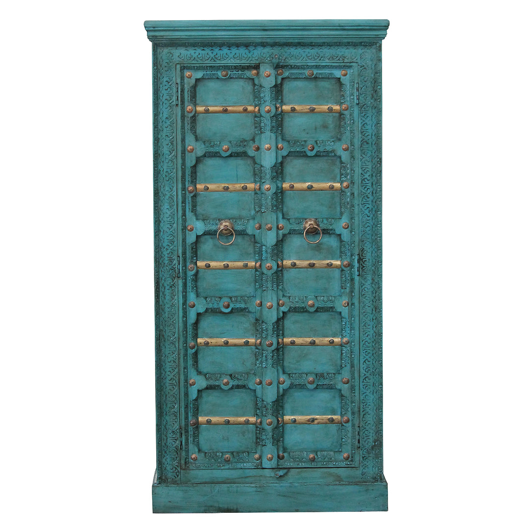 Vista frontal del armario turquesa con tallas decorativas, travesaños dorados y dos puertas de madera de mango.