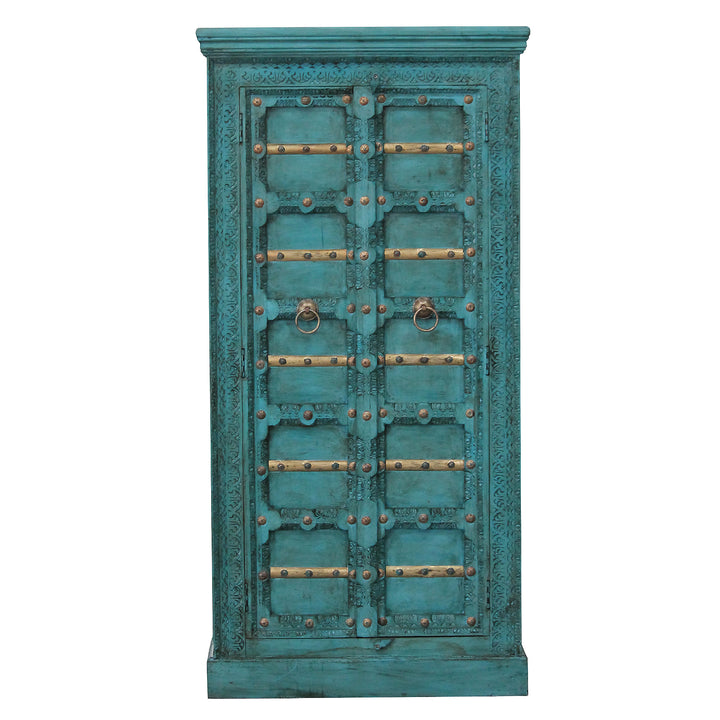 Vista frontal del armario turquesa con tallas decorativas, travesaños dorados y dos puertas de madera de mango.