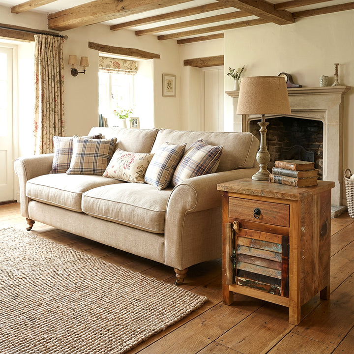Kommode aus Holz im Wohnzimmer neben Sofa, warme Landhaus-Atmosphäre, natürliches Licht