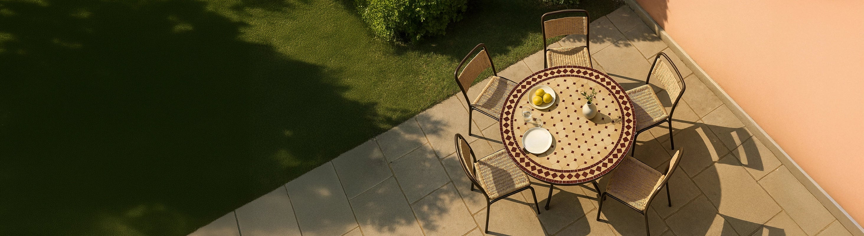 Mesas mosaico Ø100 – Gran mesa redonda de mosaico de Ø100 cm con azulejos de zellige y varias sillas en la terraza del jardín a vista de pájaro con el cálido sol