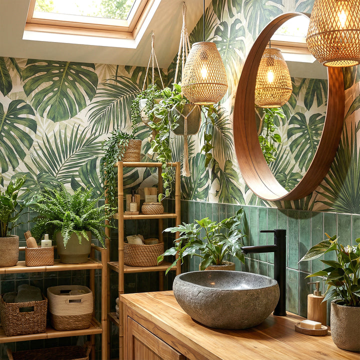 Lavabo sobre encimera de piedra de río en baño spa verde sobre tocador de madera, combinado con accesorios negros y ambiente vegetal