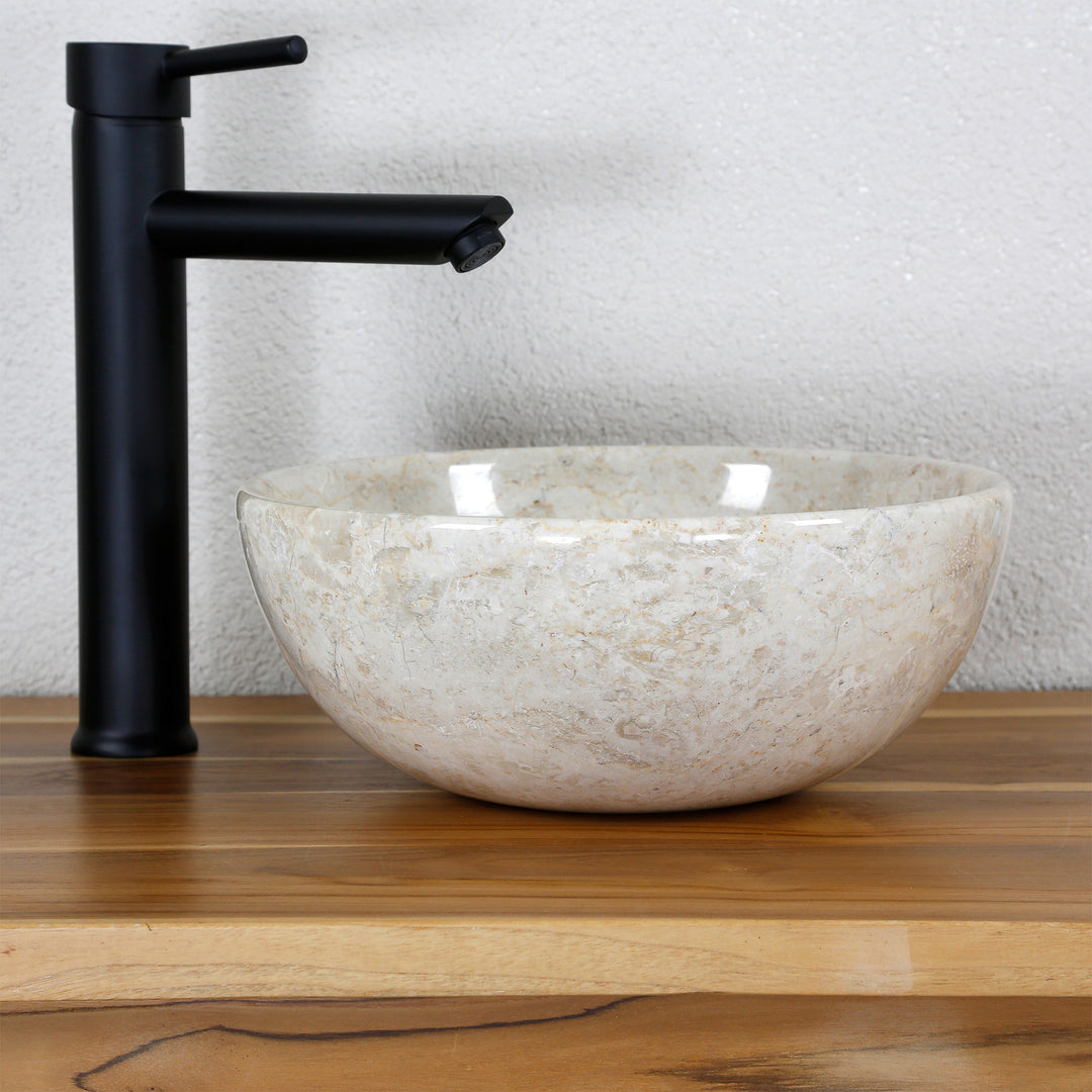 Lavabo sobre encimera de mármol brillante sobre una superficie de madera con un accesorio negro en un ambiente de estudio claro y minimalista