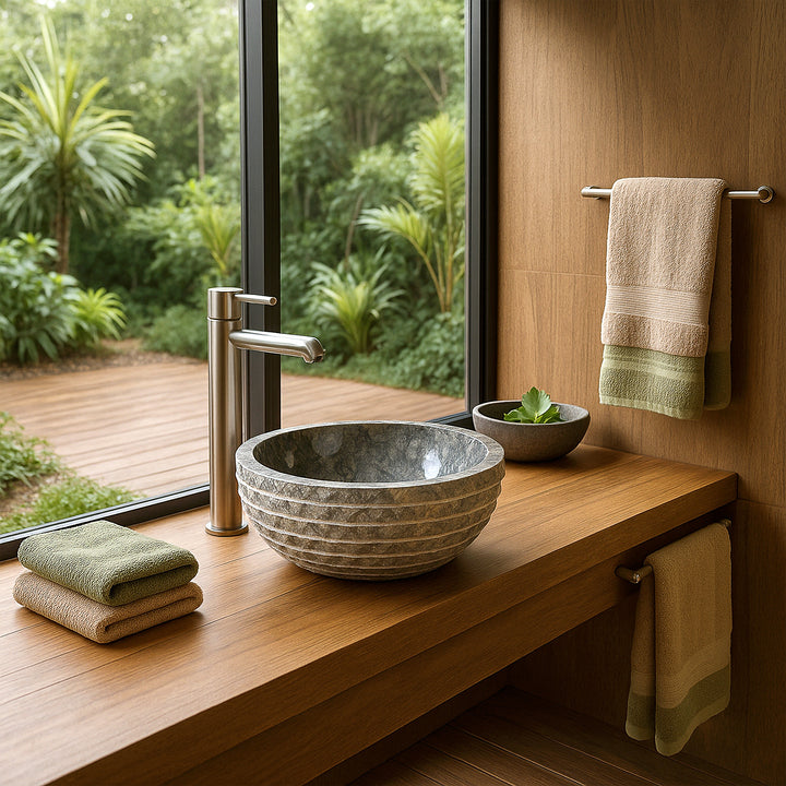 Lavabo de piedra con encimera redonda en tocador, baño moderno con ventana con vista a vegetación, toallas y plantas