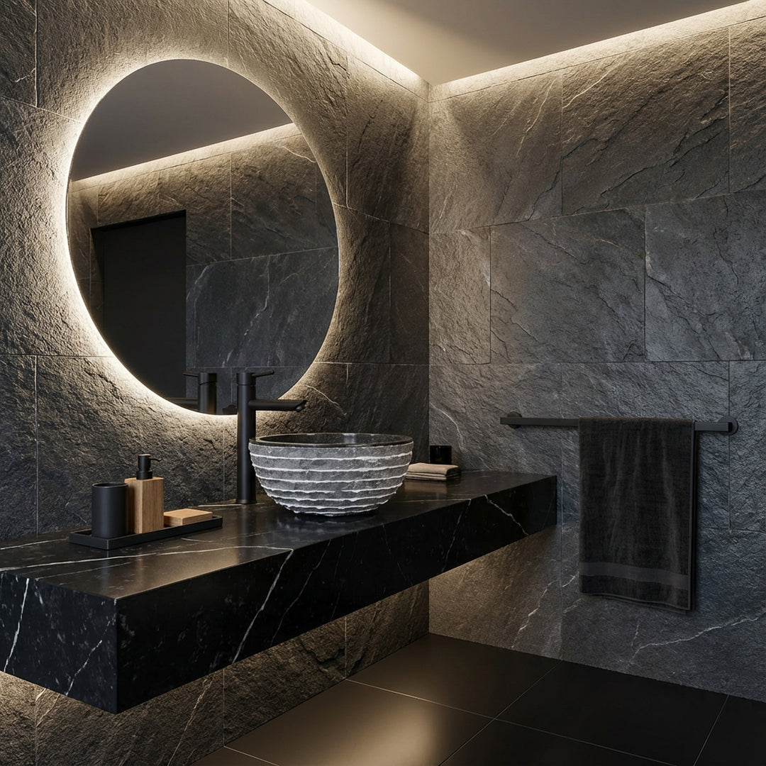 Lavabo redondo de piedra natural sobre un tocador oscuro en un moderno baño spa con espejo, grifo negro y luz indirecta