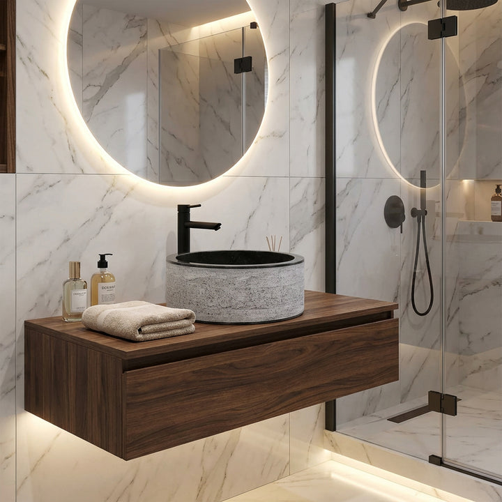 Lavabo redondo de piedra sobre consola flotante de madera, combinado de forma moderna con grifería negra en un elegante baño de diseño.