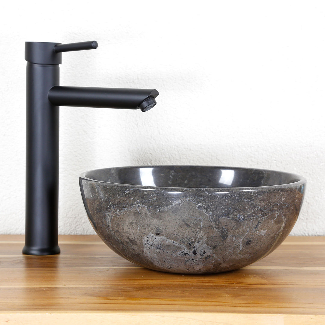 redondo Lavabo De piedra natural con vetas oscuras sobre una superficie de madera, combinado con un herraje independiente negro.