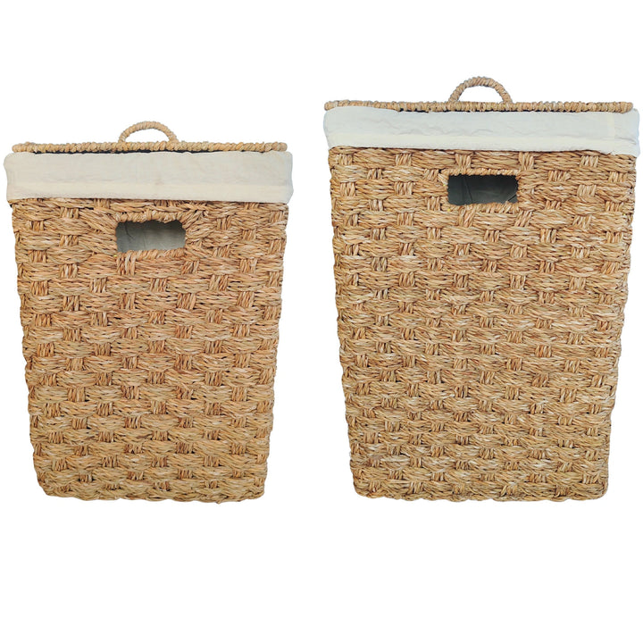 Cestas rectangulares para la ropa sucia, fabricadas en algas marinas, en un juego de dos unidades, de aproximadamente 55 y 85 litros, con tapas cerradas e inserciones de tela de colores claros.