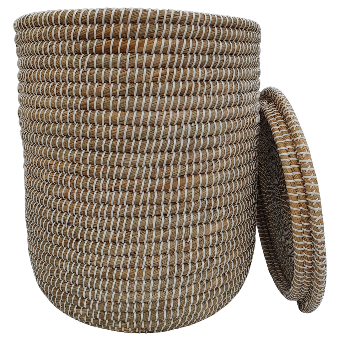 Cesto de la ropa abierto, fabricado en algas marinas en color natural/blanco, con un volumen aproximado de 65 litros y tapa que se apoya lateralmente.