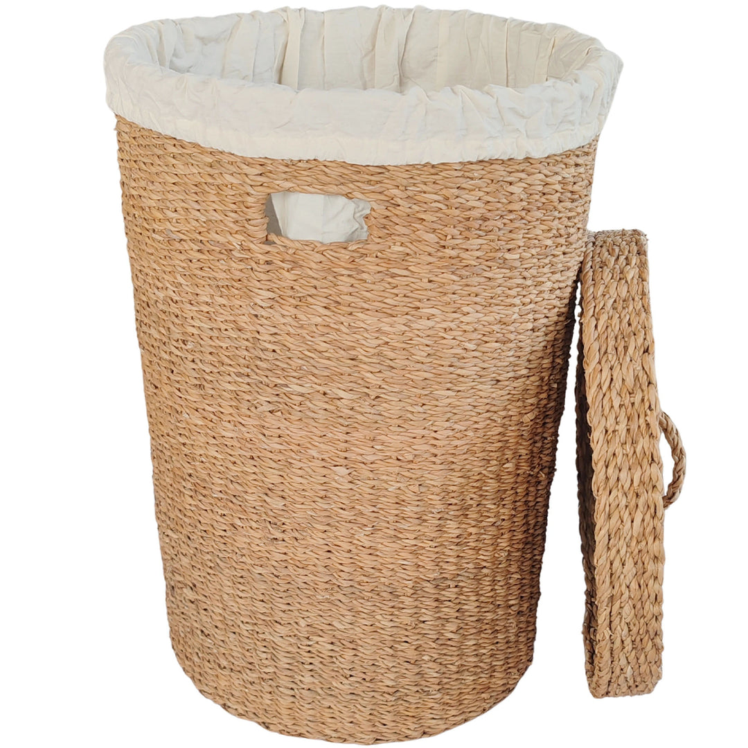 Cesta grande para la ropa sucia fabricada en algas marinas, con una capacidad de 75 litros, un forro de tela clara y una tapa que se apoya lateralmente.
