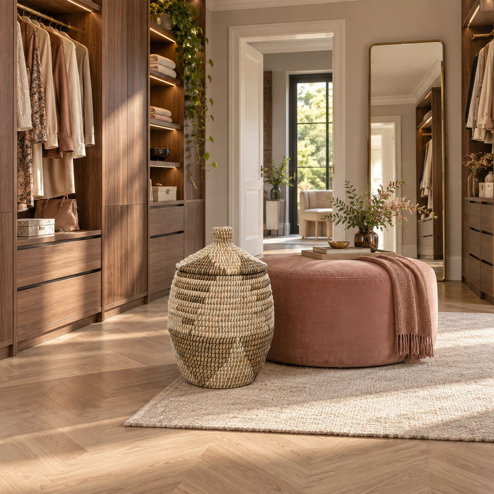 Cesto para la ropa de algas marinas en color natural/marrón/negro/blanco, con tapa y una capacidad aproximada de 30 litros, situado en el vestidor.