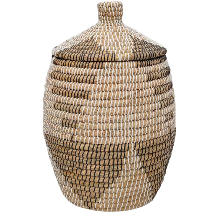Cesto para la ropa de forma abombada, fabricado en algas marinas en colores natural, marrón, negro y blanco, con tapa cónica y un volumen aproximado de 30 litros.