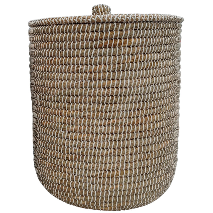 Cesto redondo para la ropa de algas marinas en color natural/blanco, con tapa cerrada y un volumen aproximado de 65 litros.