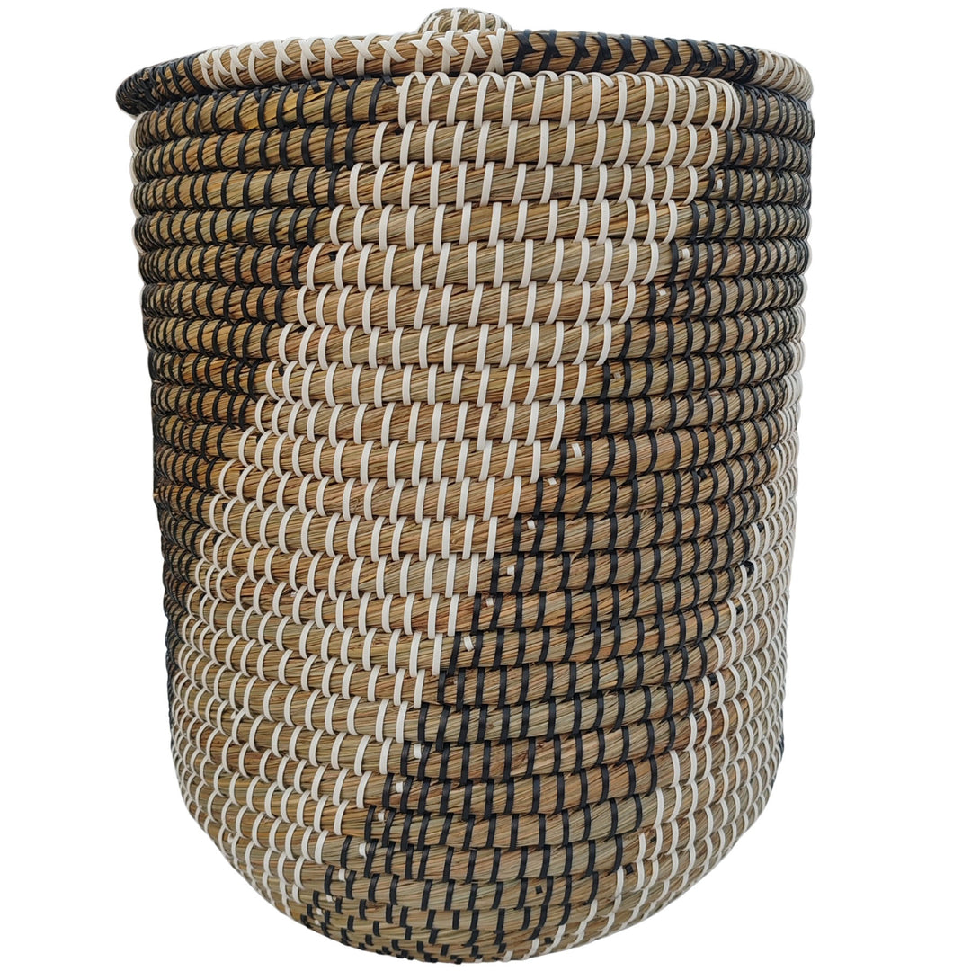Cesto redondo para la ropa de algas marinas en colores natural, negro y blanco, con tapa cerrada y un volumen aproximado de 40 litros.