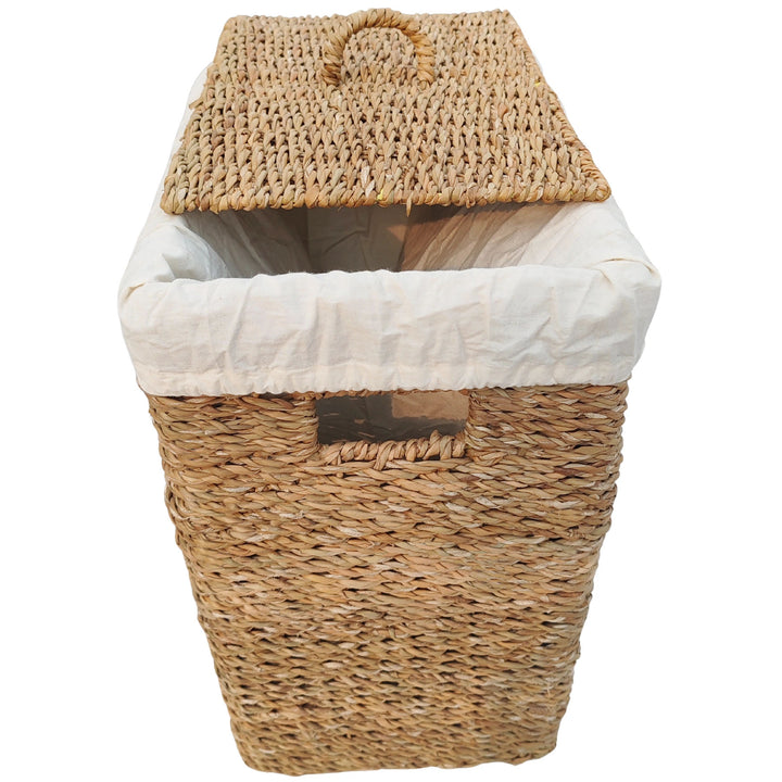Cesto rectangular para la ropa, fabricado en algas marinas, con una capacidad de 50 litros, un forro de tela clara y una tapa colocada en diagonal.