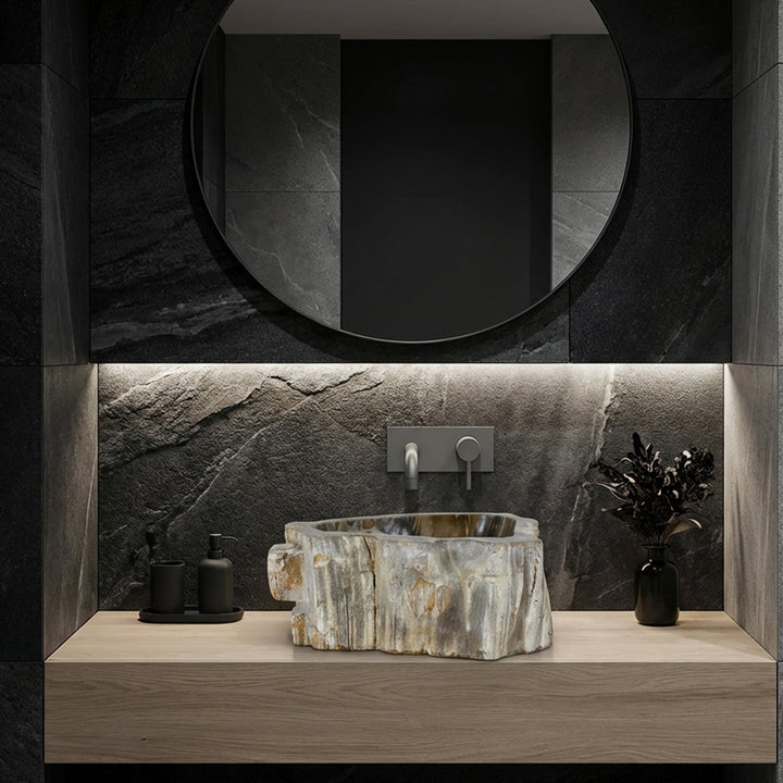Lavabo lavabo de piedra como lavabo sobre encimera, ambiente de baño moderno con azulejos de piedra natural oscura, líneas claras e iluminación sutil.