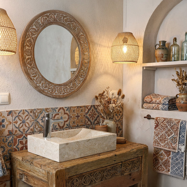 Lavabo sobre encimera rectangular de piedra natural clara sobre un lavabo de madera en un baño oriental con azulejos estampados y luz cálida